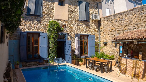 Un bâtiment en pierre doté d’une piscine, d’un espace extérieur aménagé pour s’asseoir et d’un bar.