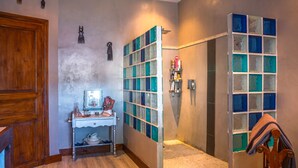 Une salle de bain avec un meuble-lavabo en bois, un miroir, un lavabo et une douche dotée d’une paroi en verre.