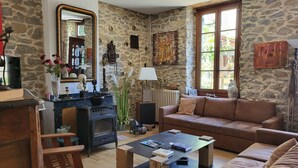 Un salon chaleureux avec un mur en pierre, une cheminée, un canapé et une table basse.