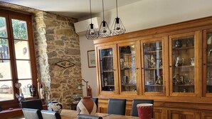 Un coin repas avec une table et des chaises en bois, un mur en pierre et un buffet en bois doté de portes en verre.