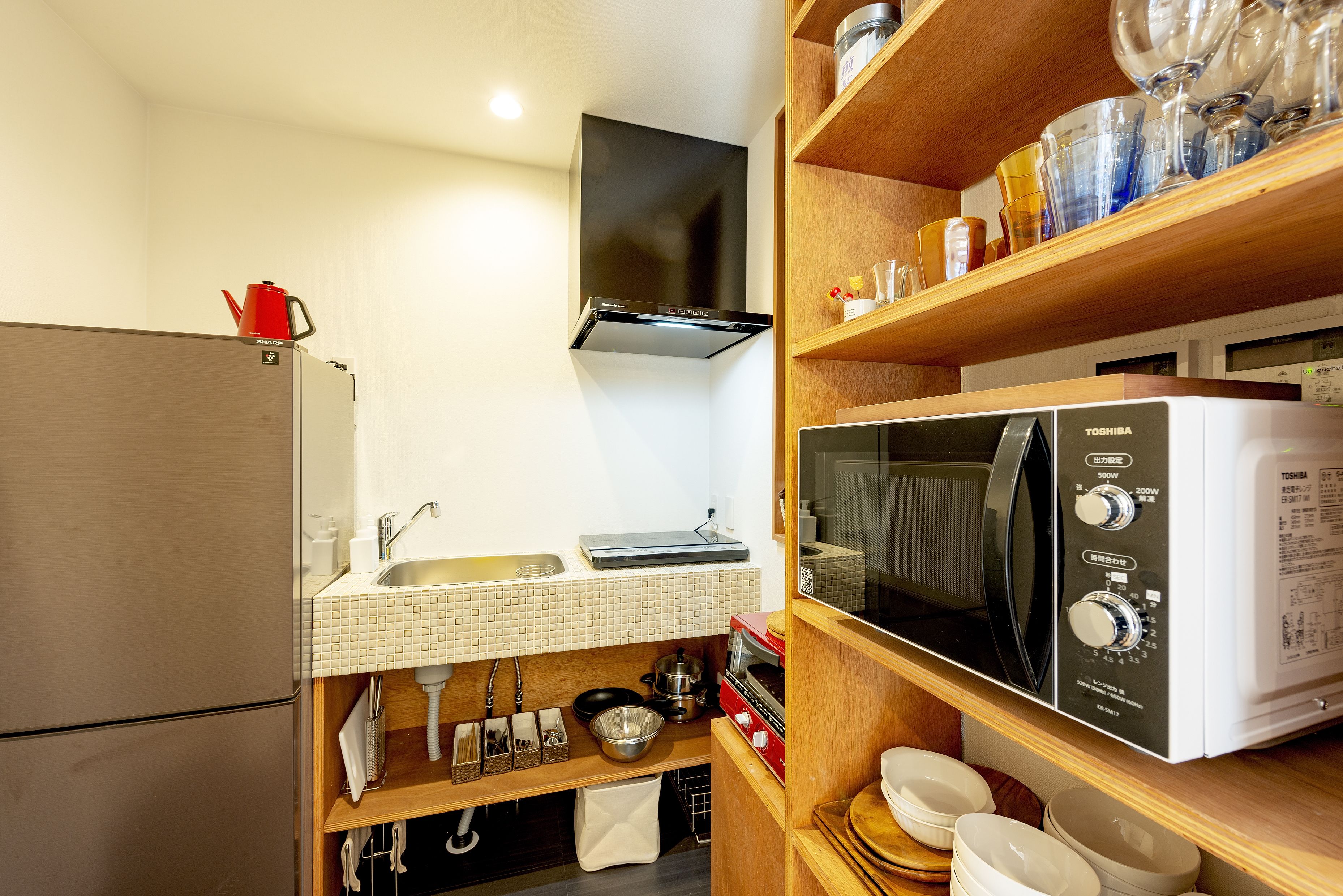 A compact kitchen with a refrigerator, sink, microwave, and stove.