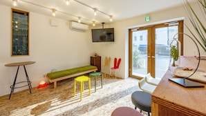 A modern room with a green sofa, a wooden table, and a TV mounted on the wall. - Plat Hostel Keikyu Asakusa Karin (Tokyo)