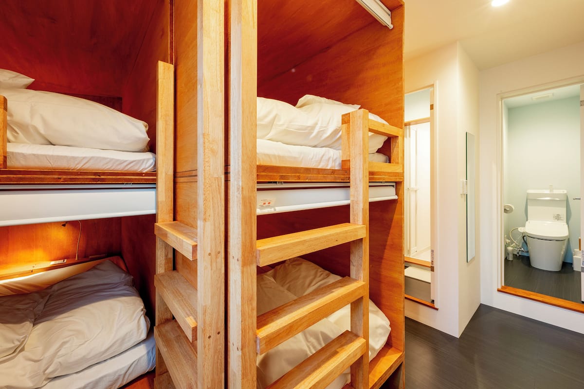 Dormitorio con literas de madera y ropa de cama blanca.