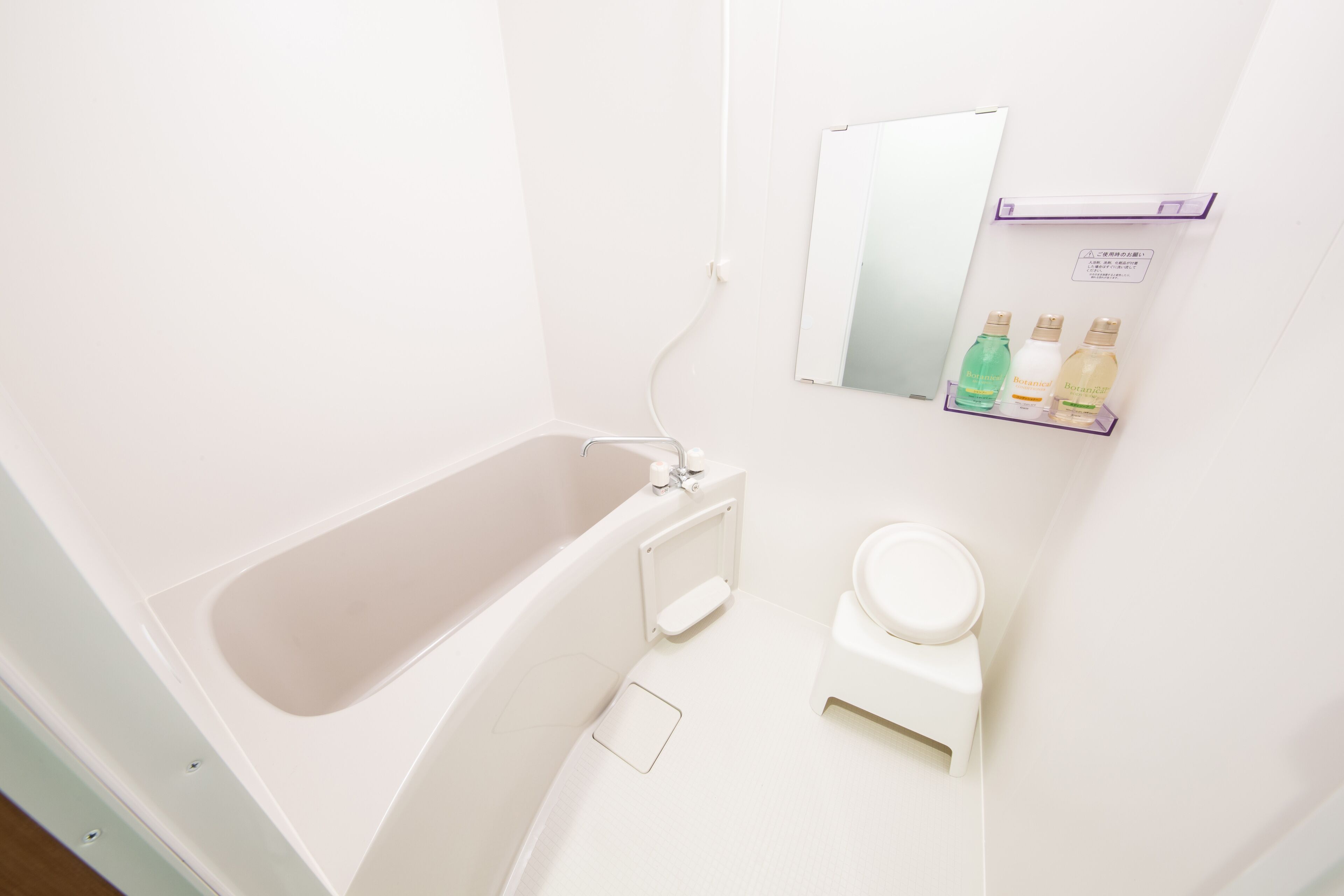 A bathroom with a bathtub, toilet, and a shelf with toiletries.