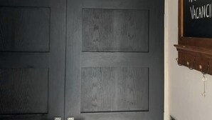 Entrada de un hotel con un letrero que dice "HOTEL" sobre una puerta de madera oscura. A la derecha, hay una pizarra con el letrero "NO DISPONIBLE".