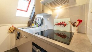 A modern kitchen with a built-in stove, a window above the sink, and a small window on the left.