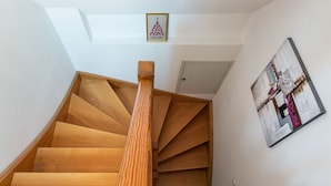 A wooden spiral staircase with a handrail, leading to a door.