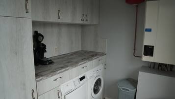 Un espace buanderie comprenant un lave-linge, un sèche-linge et une petite poubelle.