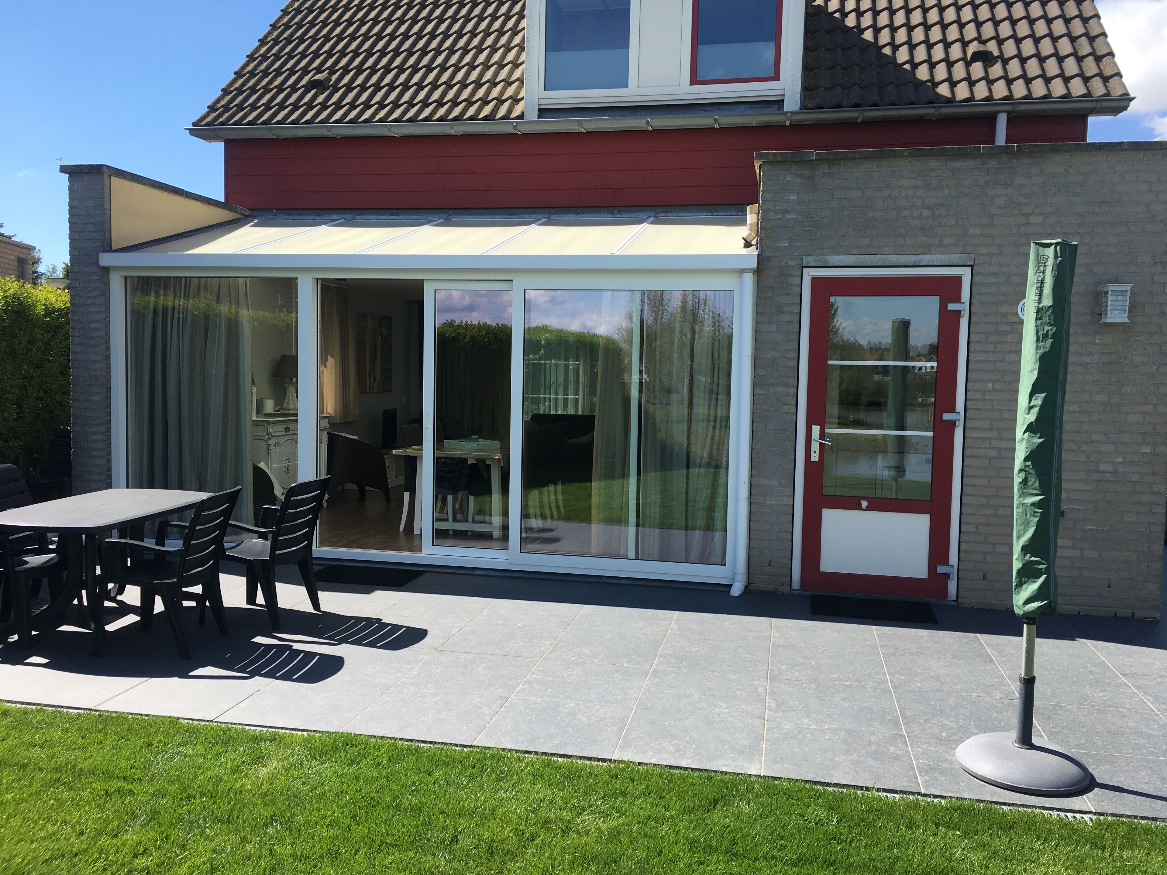 A house with a patio, a dining table with chairs, and a covered outdoor area.
