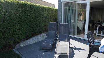 Eine Terrasse mit zwei Liegestühlen, einem Tisch und einem Stuhl.