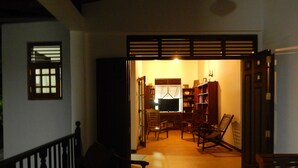 An interior view of a traditional Japanese-style room with tatami flooring, a low wooden table, and a built-in shelf with books.