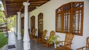 A covered outdoor seating area with wooden chairs and a potted plant.