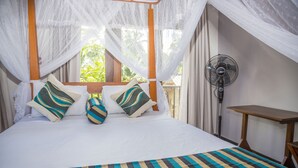 A bed with a striped bedspread, a canopy, and two pillows with striped patterns.