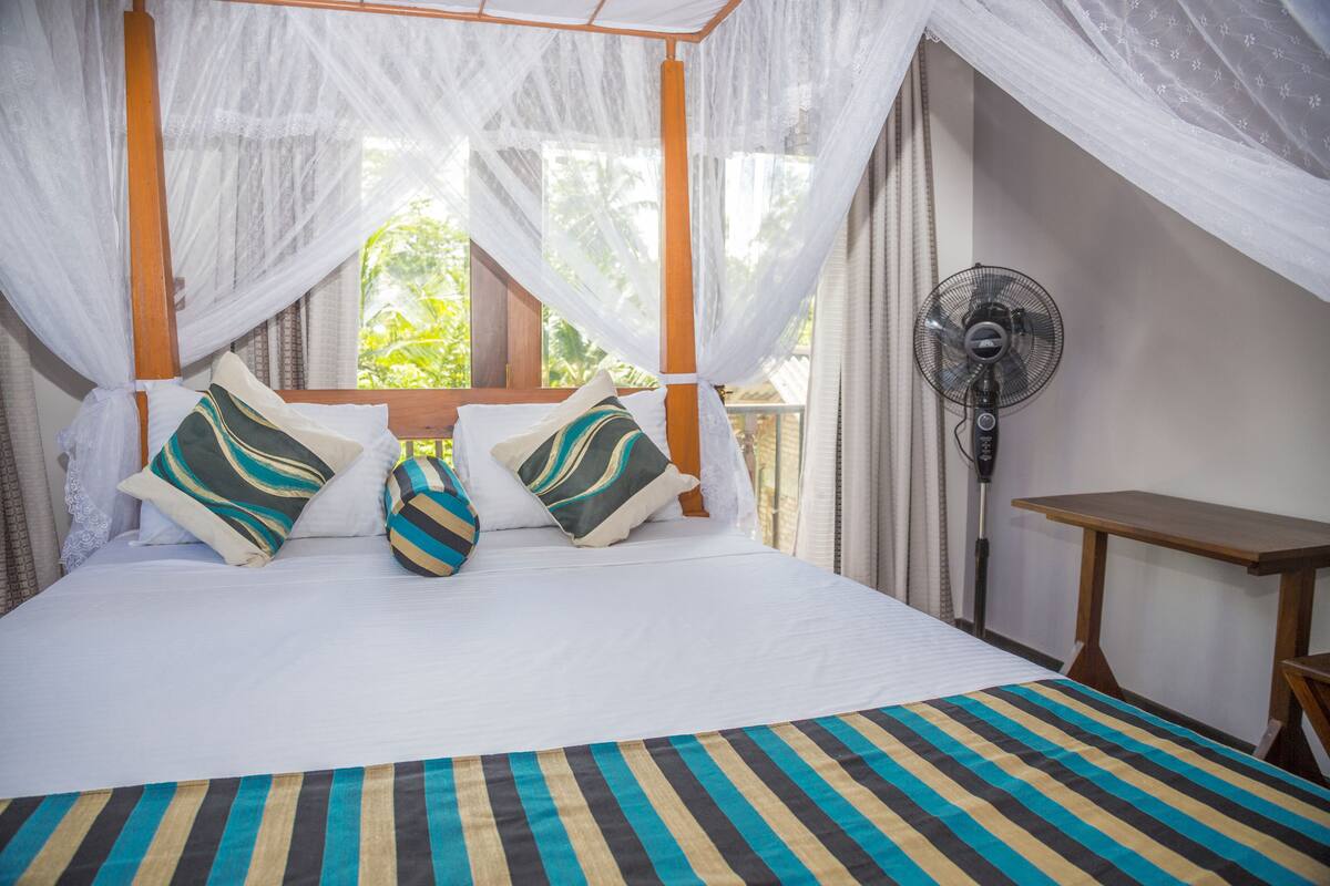 A bed with a striped bedspread, a canopy, and two pillows with striped patterns.