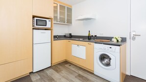 Una cocina funcional con microondas, tostadora, lavabo y lavadora.