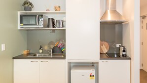 Una cocina pequeña con microondas, hervidor y cafetera sobre la encimera.