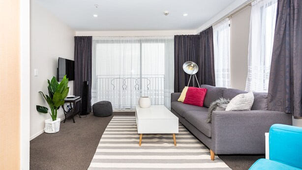 Una sala de estar moderna con un sofá gris, una mesa de centro blanca y sillones azules.