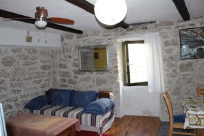 Una habitación rústica con techo de madera, una cama con ropa de cama a rayas, una mesa con mantel estampado y un espejo en la pared.