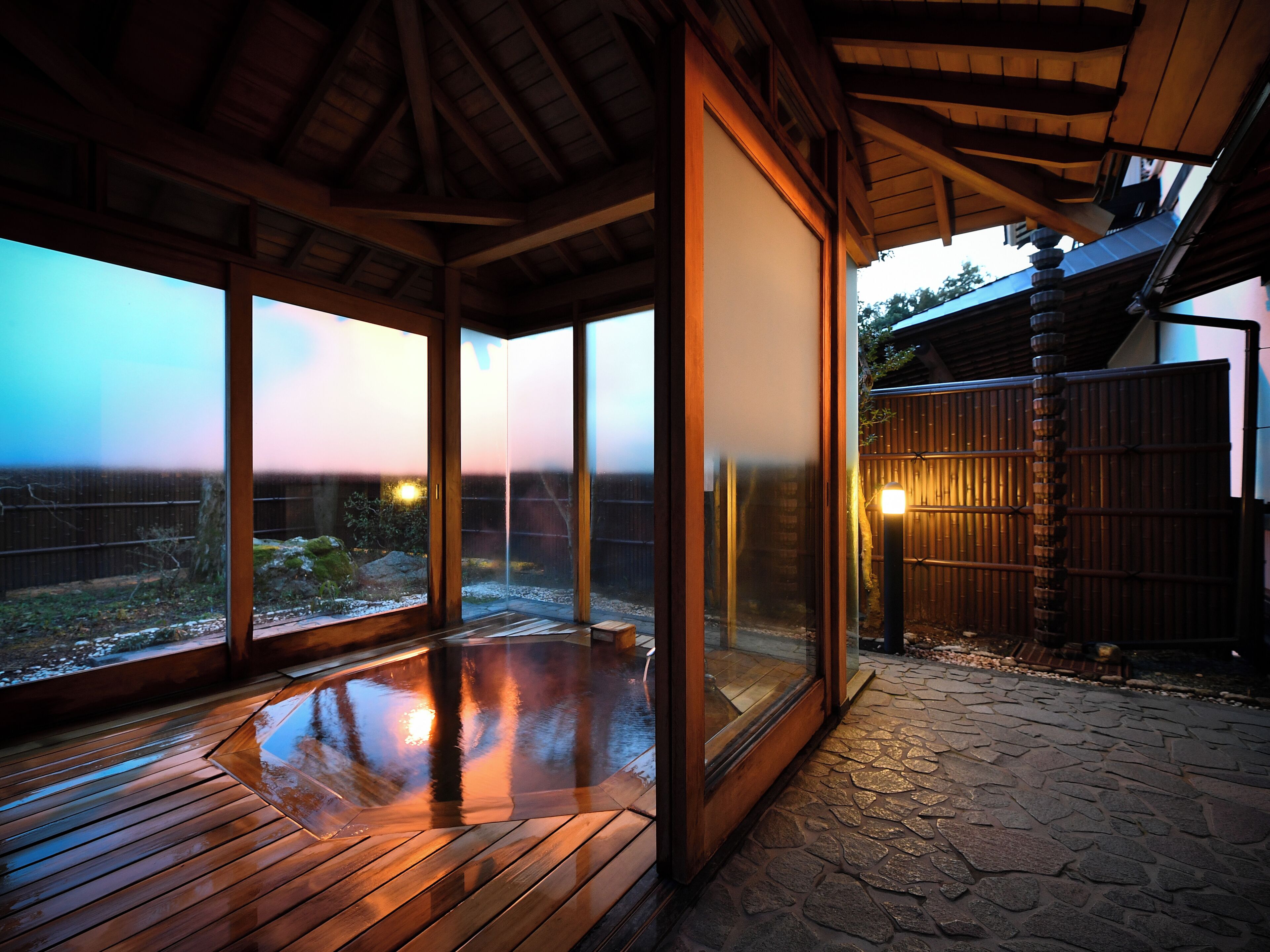 Una terraza de madera con puertas de vidrio que dan a un jardín.