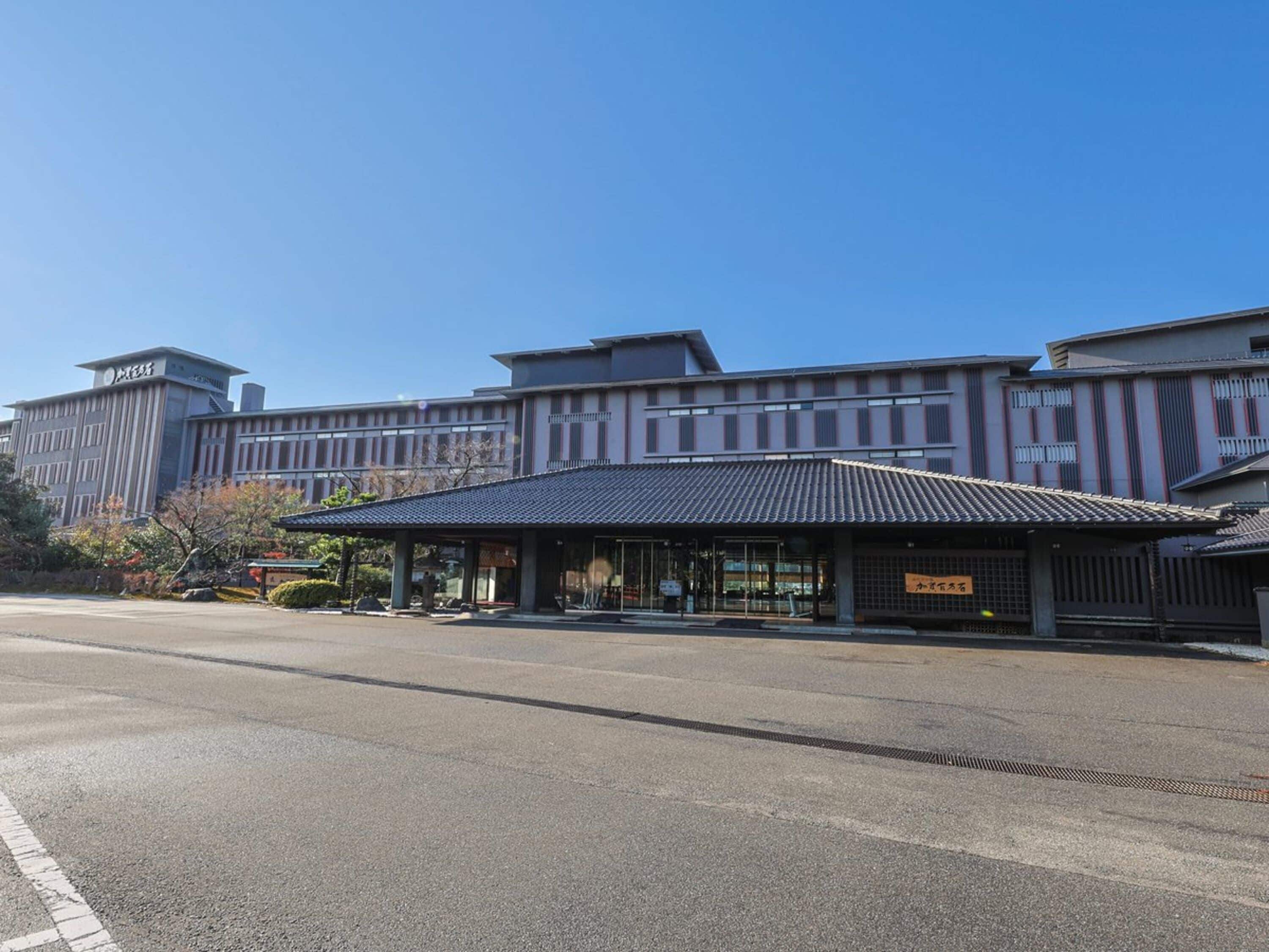 A modern building with a covered entrance and a parking lot in front.