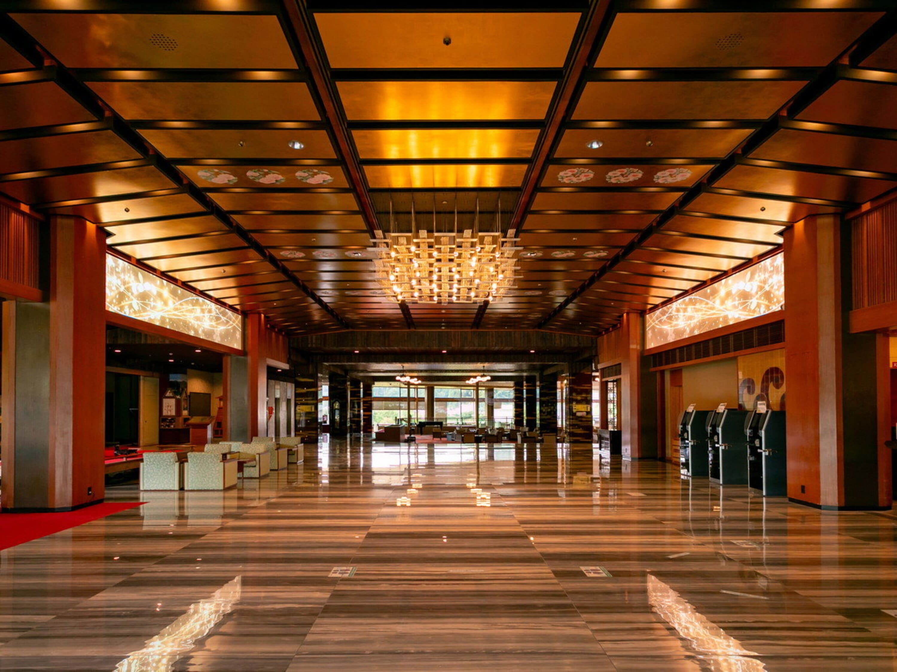 A spacious lobby with a polished marble floor, a large chandelier, and a reception desk.