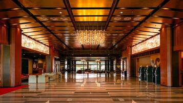 A spacious lobby with a polished marble floor, a large chandelier, and a reception desk.