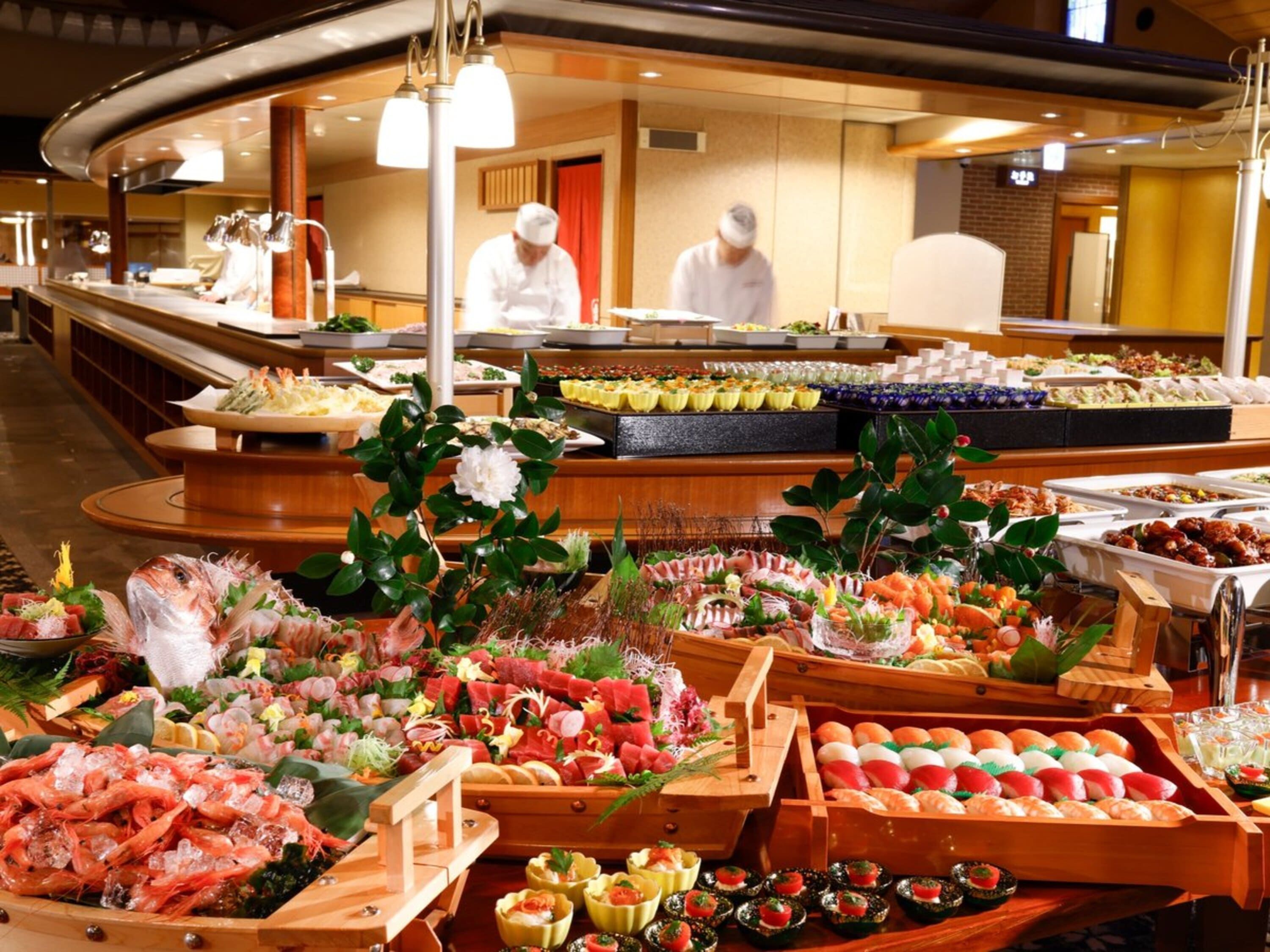 A buffet with various food items and a chef in the background.