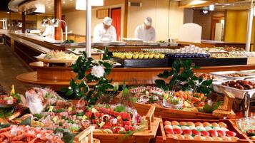 A buffet with various food items and a chef in the background.