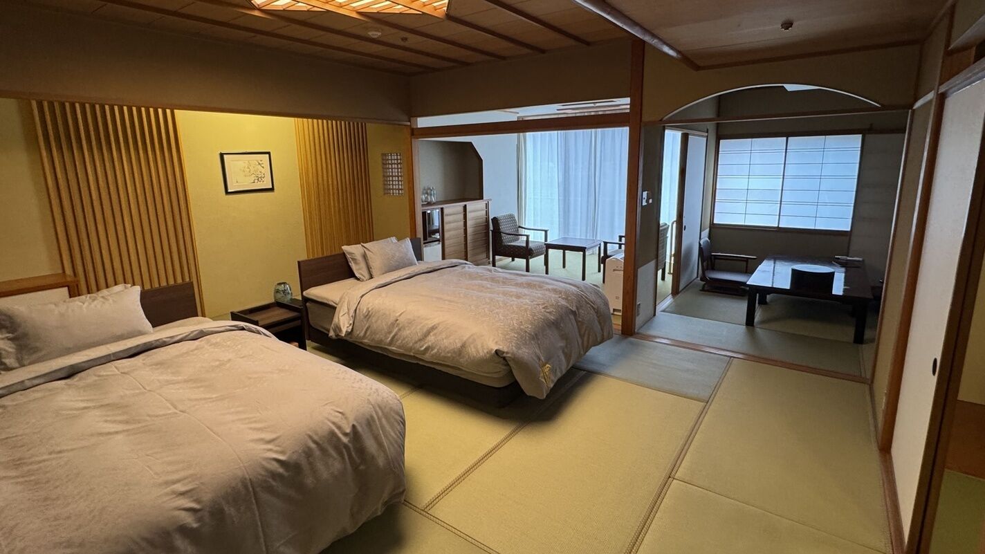 Quarto de hotel com duas camas, uma escrivaninha e vista para o exterior.