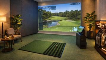 Una stanza con un grande schermo che mostra un campo da golf, un golf cart e un putting green.
