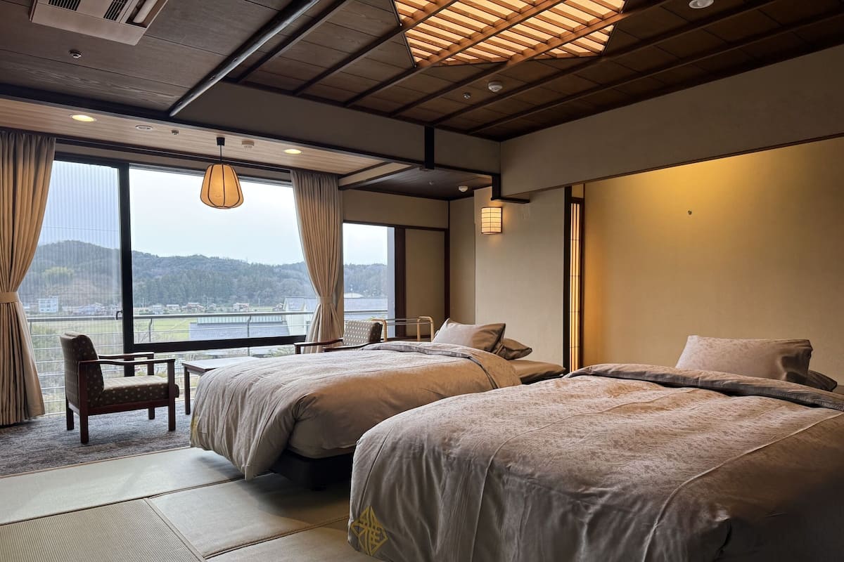 A hotel room with two beds, a chair, a small table, and a view of a body of water.