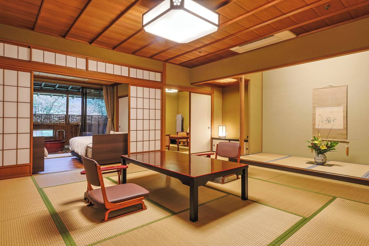 A traditional Japanese room with tatami flooring, a low table, chairs, and sliding doors.