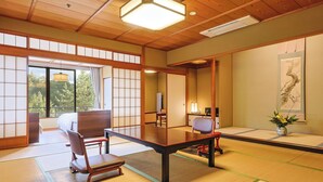 A traditional Japanese room with tatami flooring, a low table, and a sliding door leading to a balcony. - Yamashiro Onsen Miyabi no Yado Kaga Hyakumangoku (Kaga)