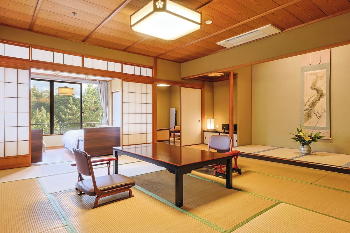 A traditional Japanese room with tatami flooring, a low table, and a sliding door leading to a balcony.