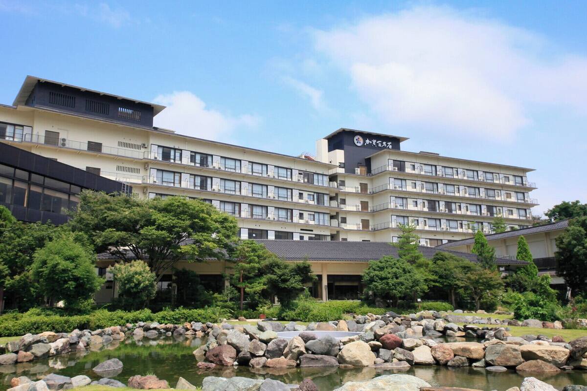 A multi-story hotel with a modern design, featuring balconies and a rooftop terrace.