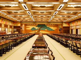 Un salón de conferencias con filas de mesas y sillas, un mural grande en la pared de fondo e iluminación empotrada en el techo.