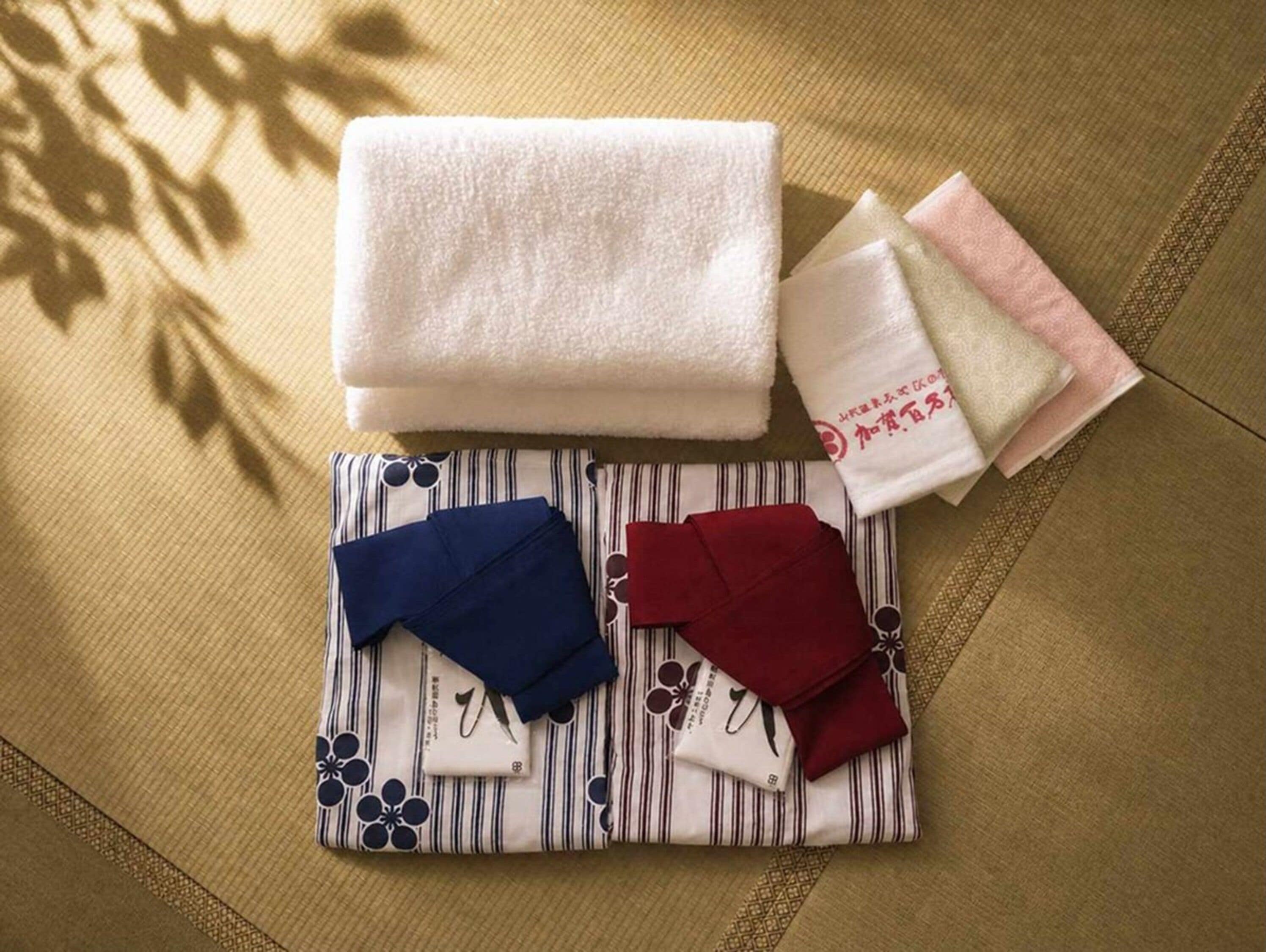 A neatly arranged set of towels and folded garments on a textured fabric surface.