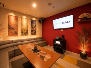 A modern living room with a sofa, a coffee table with a vase, and a flat-screen TV mounted on a red wall.
