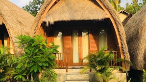A bungalow-style hotel with thatched roofs, a swimming pool, and tropical landscaping. - The Sandat Bungalow (Penida Island)