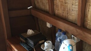 A wooden desk with a remote control, two white cups on saucers, a tissue box, and a blue kettle. - The Sandat Bungalow (Penida Island)