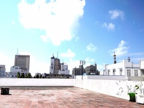 Una terrazza sul tetto con vista sugli edifici della città, una parete bianca e un pavimento piastrellato.