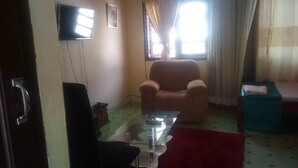 A living room with a sofa, a television mounted on the wall, and a window with curtains.