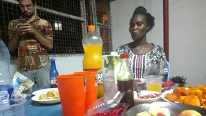 A dining table with various food items and drinks, including a plate of fruits, a bottle of juice, and a plastic cup.