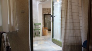 A doorway leading to a room with a stone wall, a wooden chair, and a small wooden stool. -  Good heavens 1, bed & bike, (Betina,Murter)