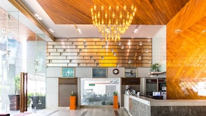 A modern reception area with a wooden ceiling, a chandelier, a reception desk, and a glass wall. - Nice Residence Hotel Bangkok (Bangkok)