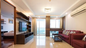 A modern living room with a sofa set, a TV, and a dining table. - Nice Residence Hotel Bangkok (Bangkok)