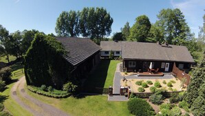 Ein zweistöckiges Haus mit gepflasterter Auffahrt, einer Veranda mit Sitzgelegenheit und einem gepflegten Garten.