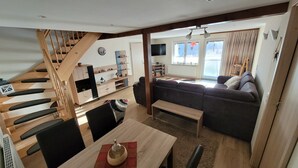 Ein modernes Wohnzimmer mit Treppe, einer Couch, einem Couchtisch und einem Fernseher.