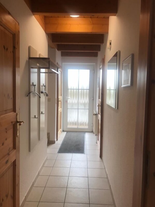 Un pasillo con puertas de madera, suelo de baldosas y techo de madera.