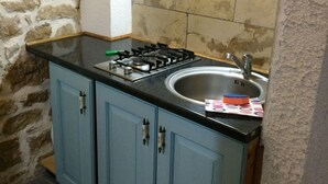 A kitchen with a gas stove, sink, and blue cabinets.